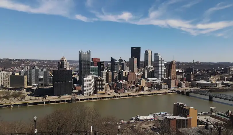 Downtown Pittsburgh skyline with the Allegheny River and bridges under a blue sky with clouds